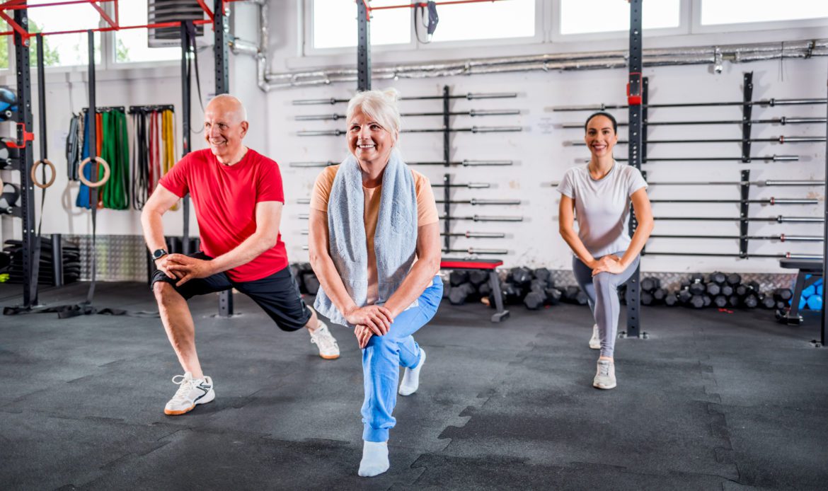 Personal Trainer mit älterem Ehepaar bei Reha-Übungen im Fitnessstudio